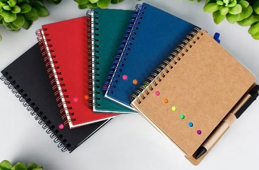 Cuaderno de espiral con líneas corporativas, bolígrafo y notas adhesivas